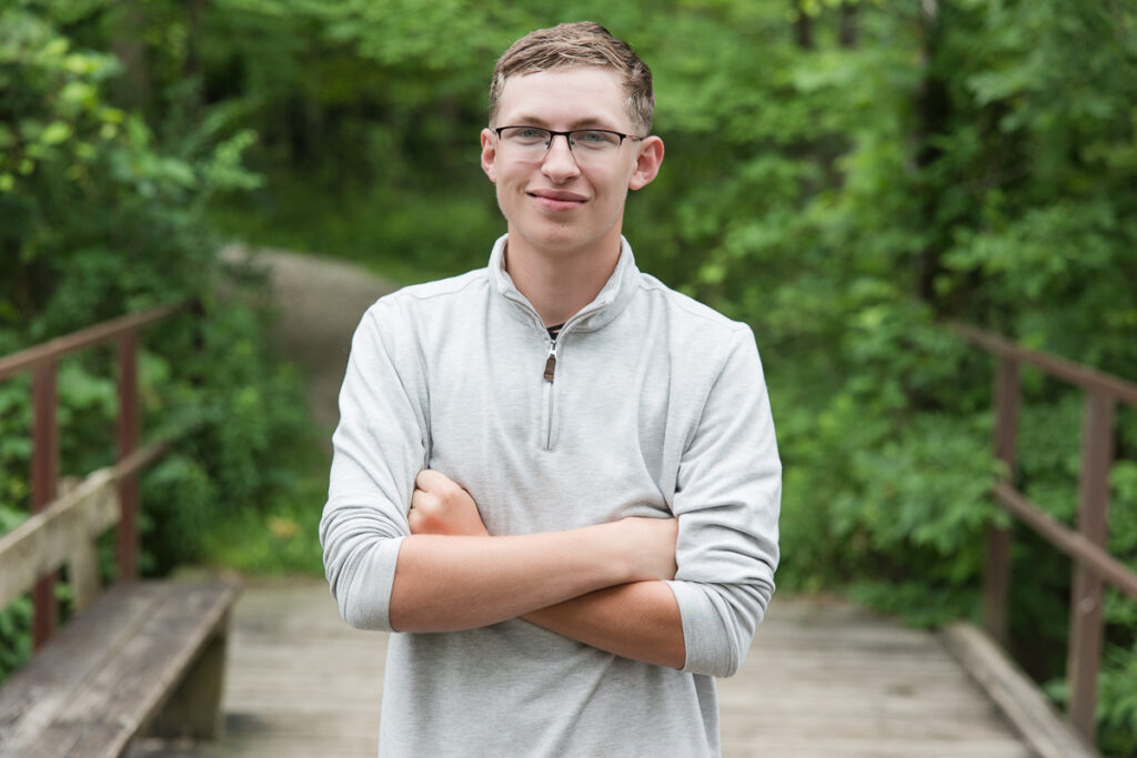 senior guy standing on a bridge smiling at the camera