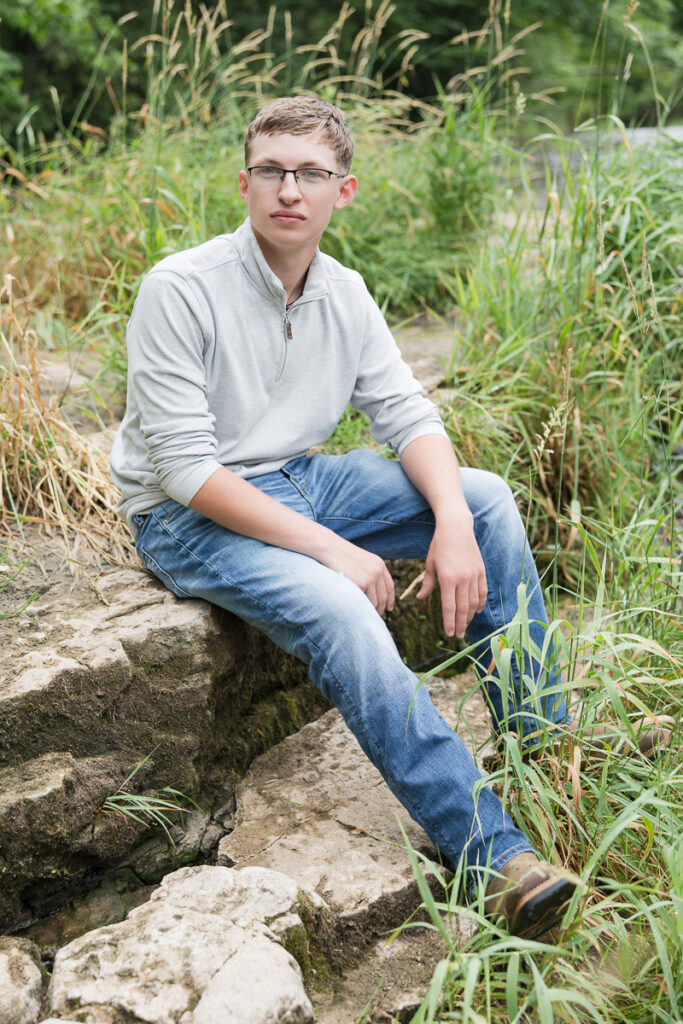 senior guy seated on a rock near a creek
