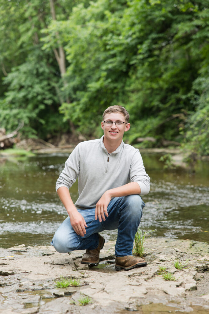 senior guy near a creek smiling at the camera