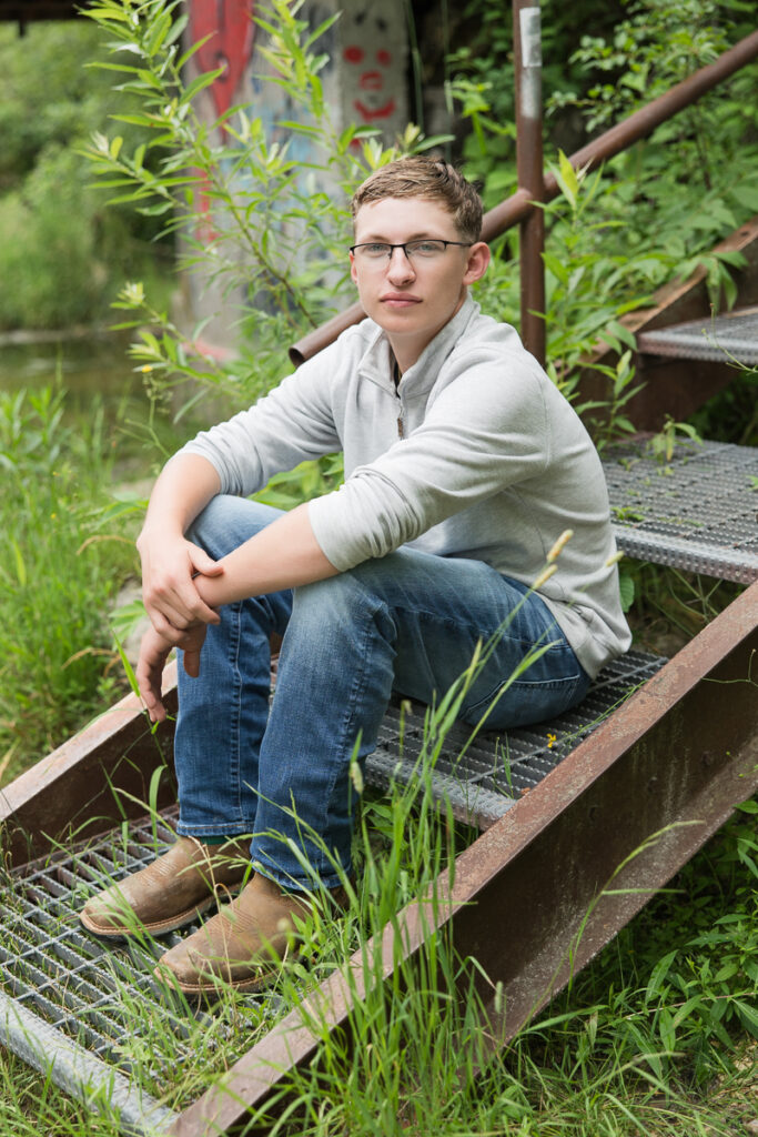 senior guy sitting on stairs looking at the camera