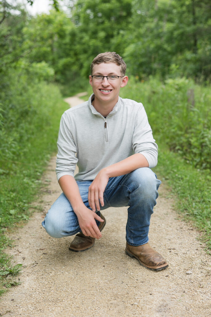 Senior guy on a wooded path smiling at the camera