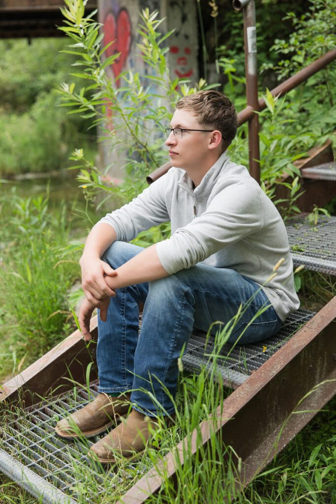 senior guy seated on the stairs looking off into the distance