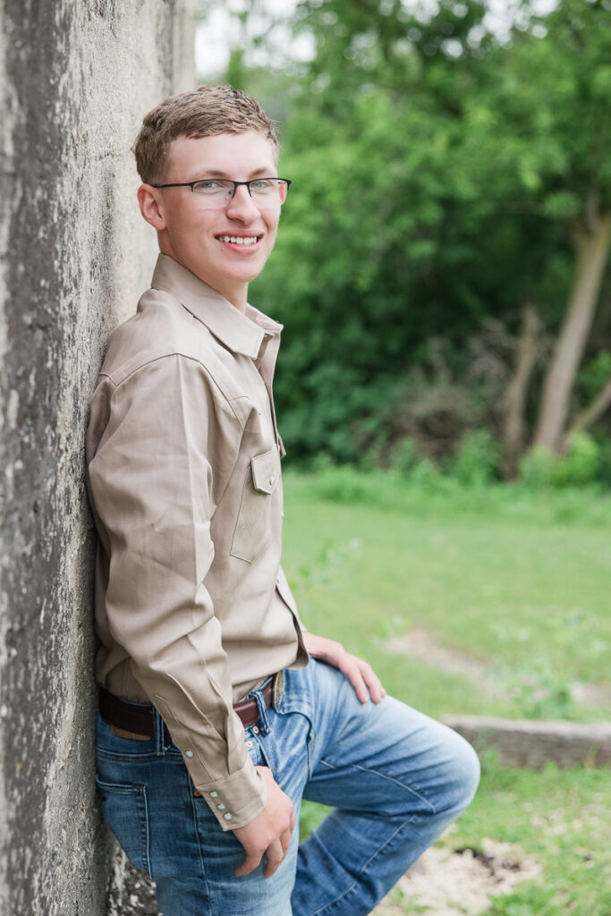 senior guy leaning against a wall and smiling