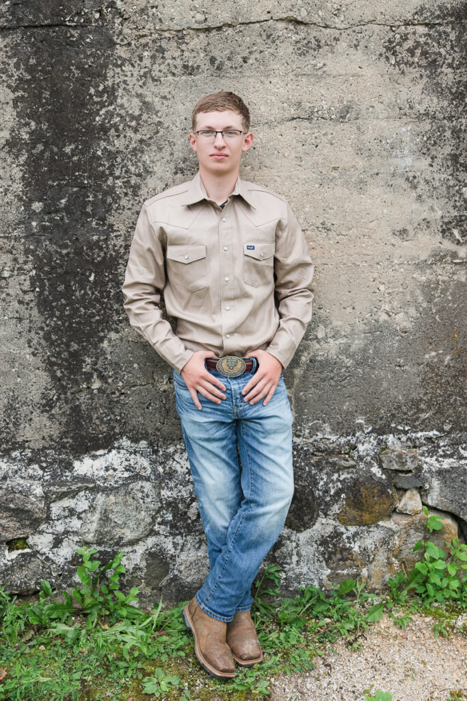 senior guy leaning against a wall and smiling