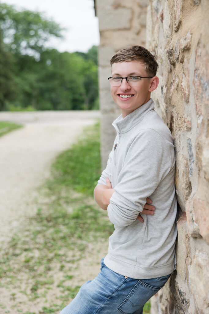 senior guy leaning against a wall and smiling