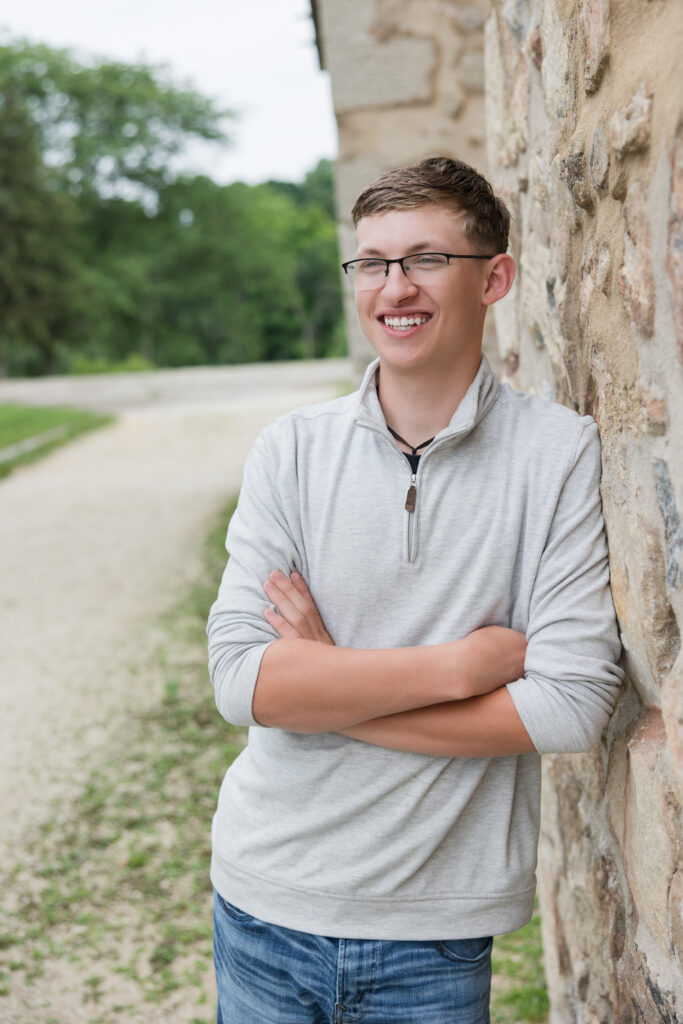senior guy leaning against a wall and smiling
