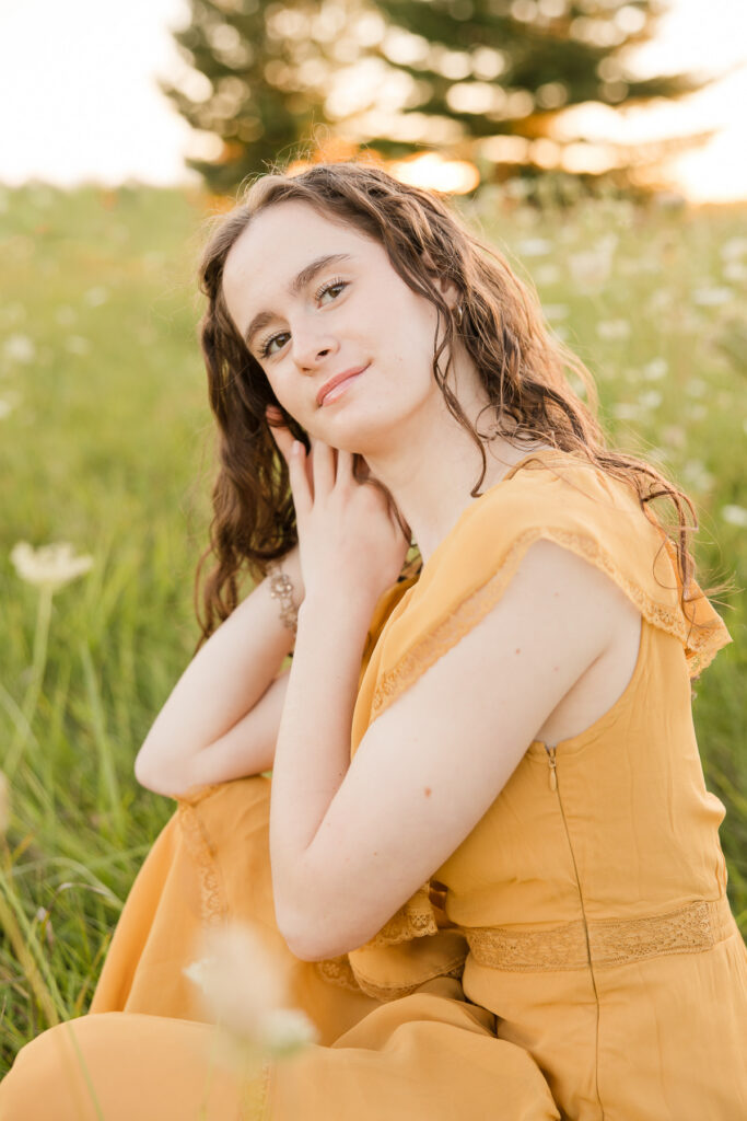 Senior portrait session in Port Washington, Wisconsin of girl crouching down in a field