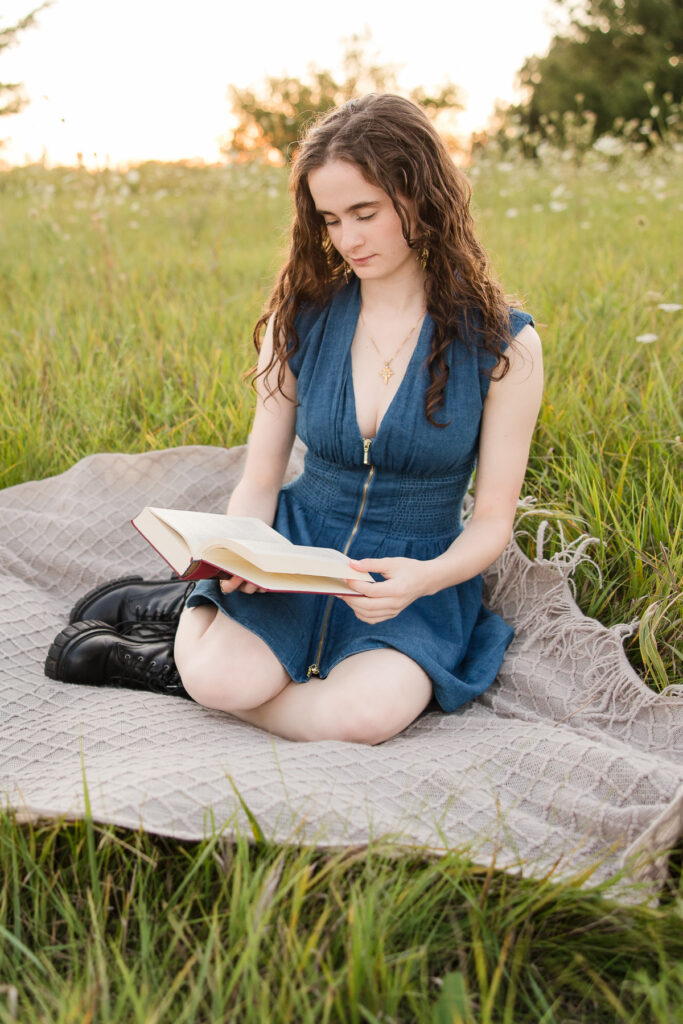 Senior girl reading a book on a blanket