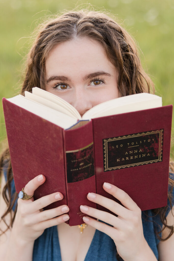Senior girl peeking out from behind a book