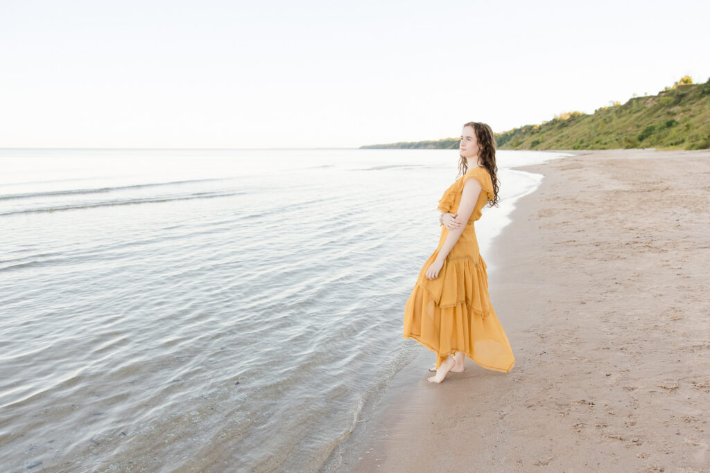 Senior girl standing on the beach and staring out into the water