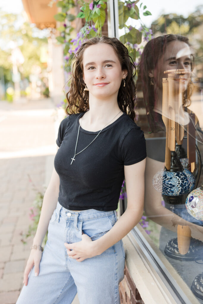 Senior girl standing against a window with a reflection of herself